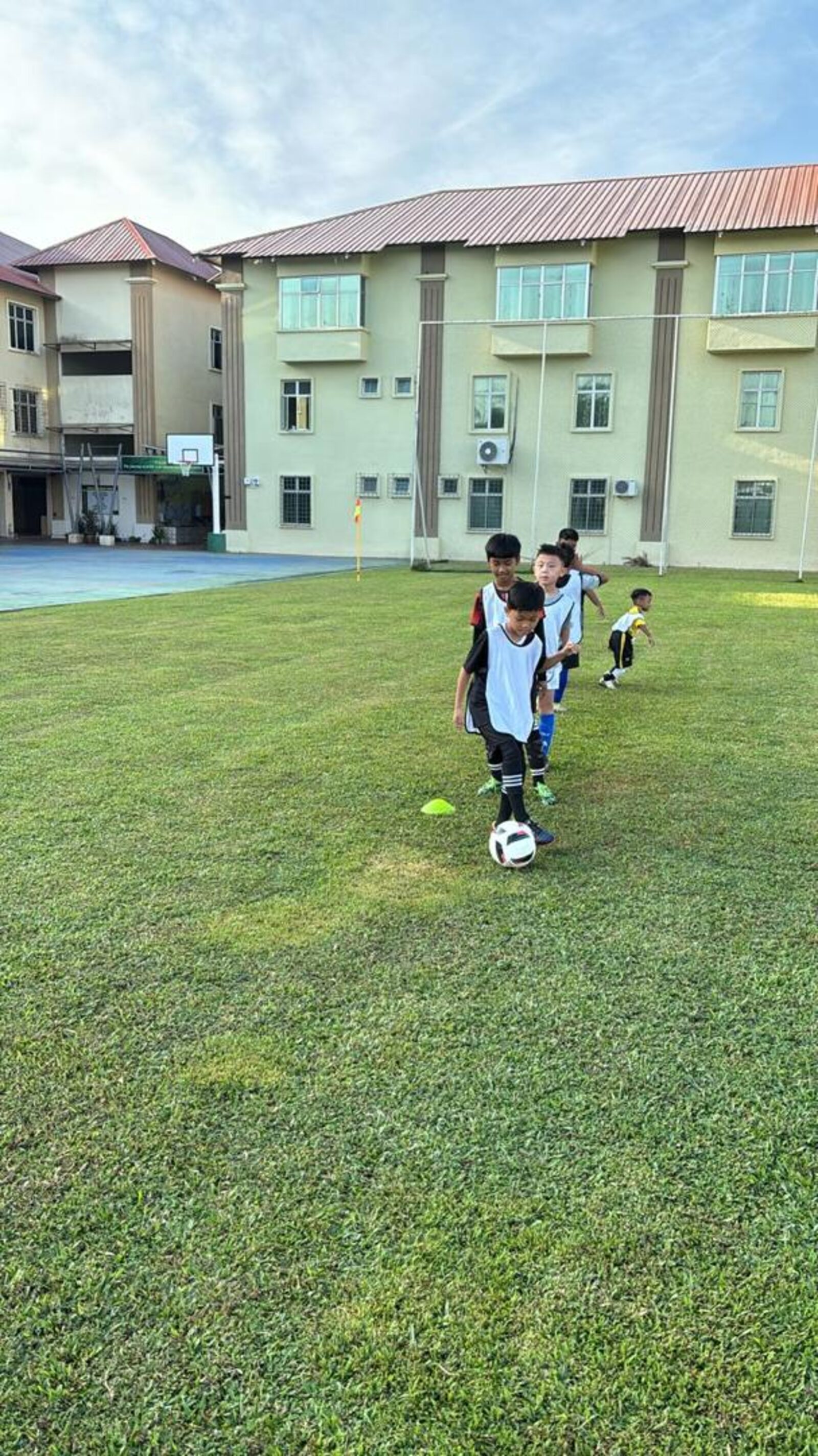 Kanak-kanak bermain bola sepak memakai vest latihan kuning