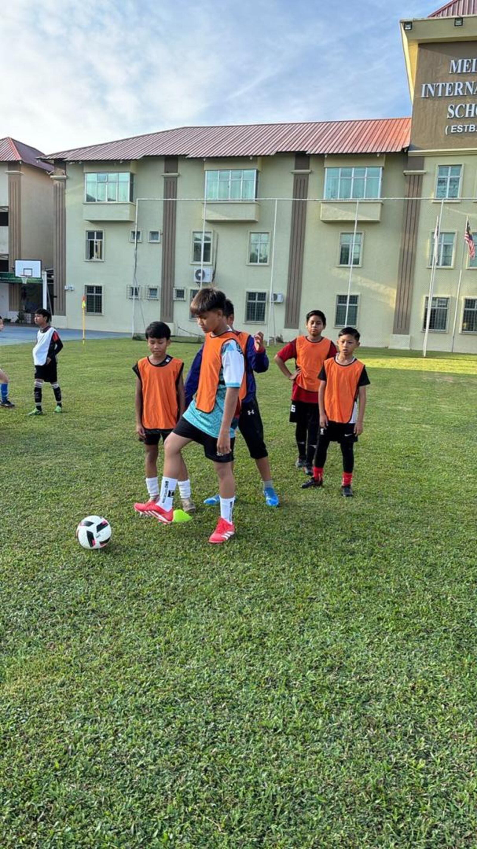 Pemain muda berlatih mengawal bola memakai vest biru muda